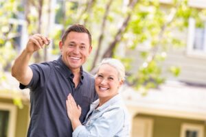 Caucasian Couple in Front of House with Keys.