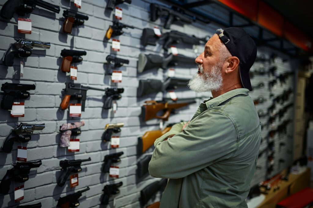 Man choosing pistol at the showcase in gun store