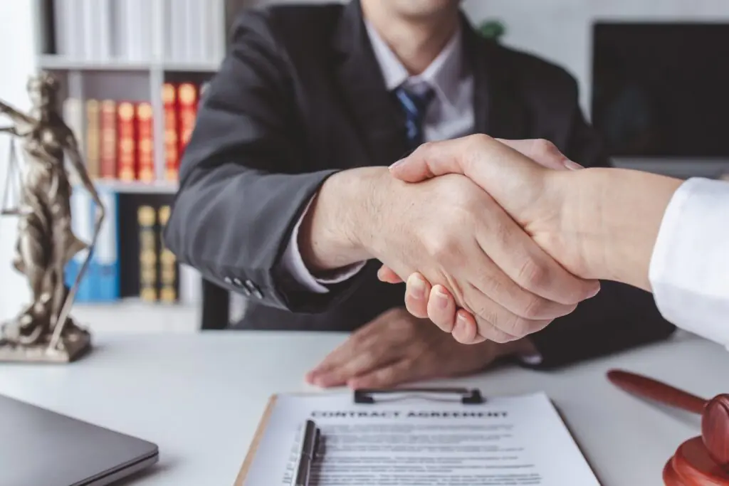 The Lawyer is currently shaking hands with the client about the success in resolving the case.