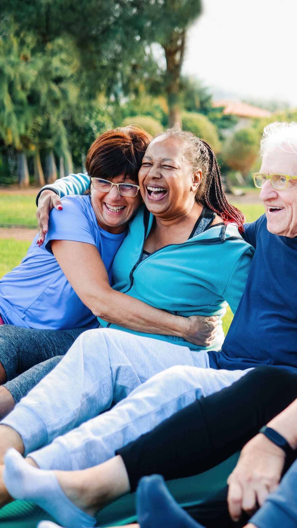 Senior friends, Happy older people have fun after yoga sport class sitting outdoors in park city.